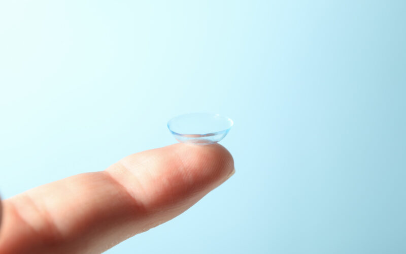Contactología en Alcañiz. Imagen dedo que sostiene una lente de contacto en primer plano y fondo azul